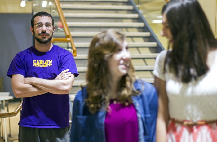 A male student poses next to two female students.