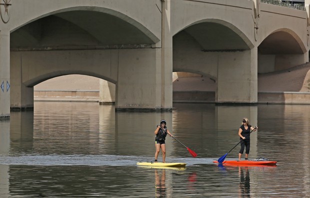 Two paddle boarders row through Tempe Town Lake.