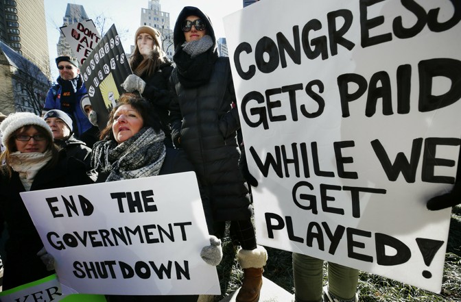 Government workers and their supporters hold signs during a protest in Boston on Friday.