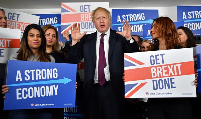 Boris Johnson stands alongside campaigners holding placards that read "Get Brexit Done" and "A Strong Economy."