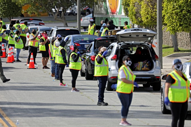 Volunteers herding a line of cards at a food bank.