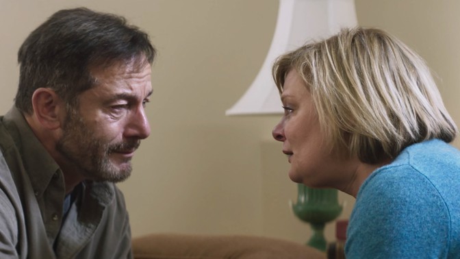 Two characters from "Mass" look emotionally into each other's eyes