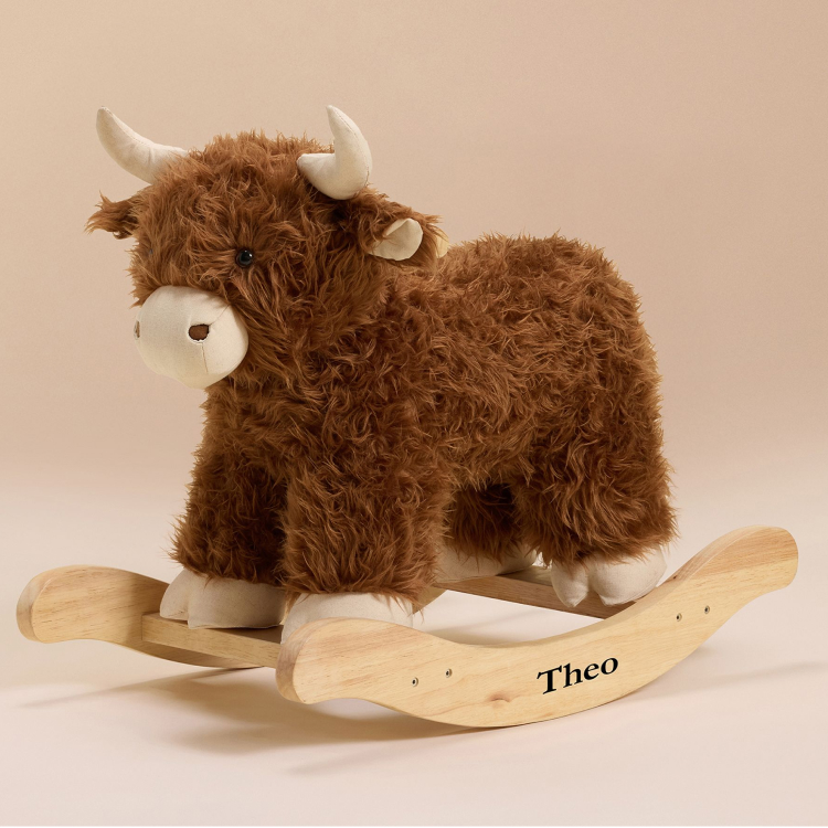 A plush brown cow rocker, with the name "Theo" written on the rocker. 