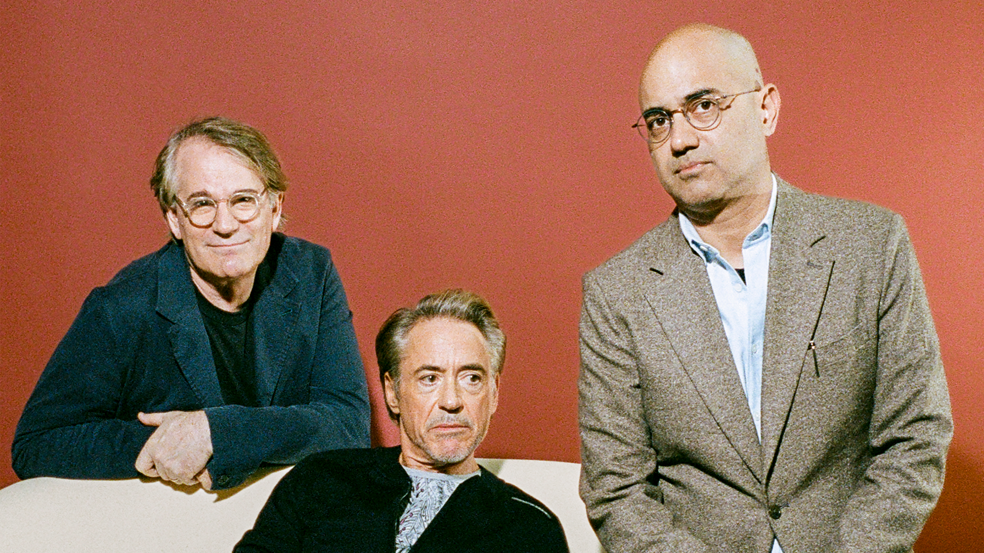 photo of Robert Downey Jr. sitting, flanked by Bartlett Sher in glasses and blue-green blazer on left and Ayad Akhtar in glasses and tan blazer on right