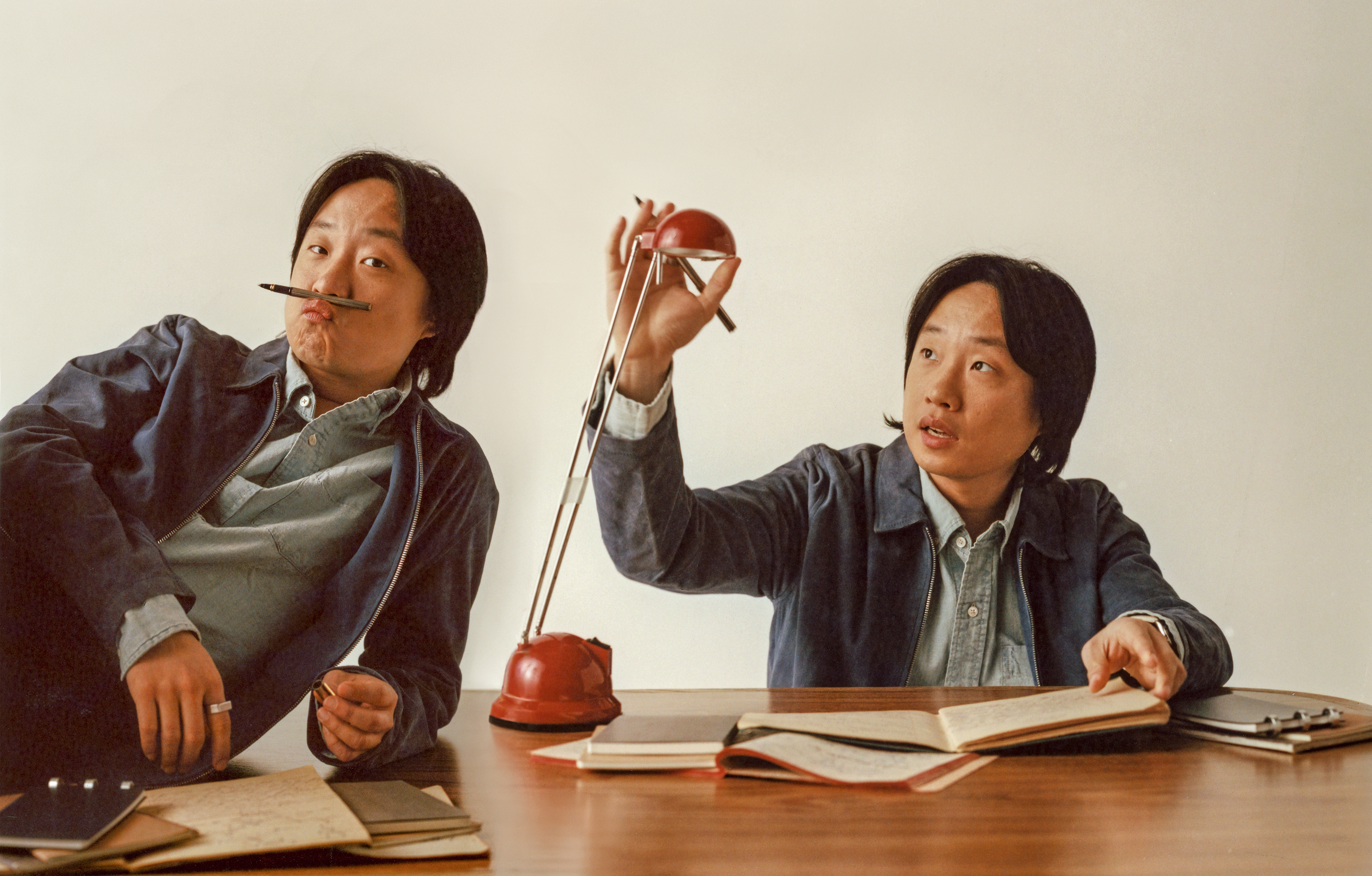 doubled photo with Jimmy O. Yang lying on desk with pen as mustache next to Jimmy adjusting a desk lamp