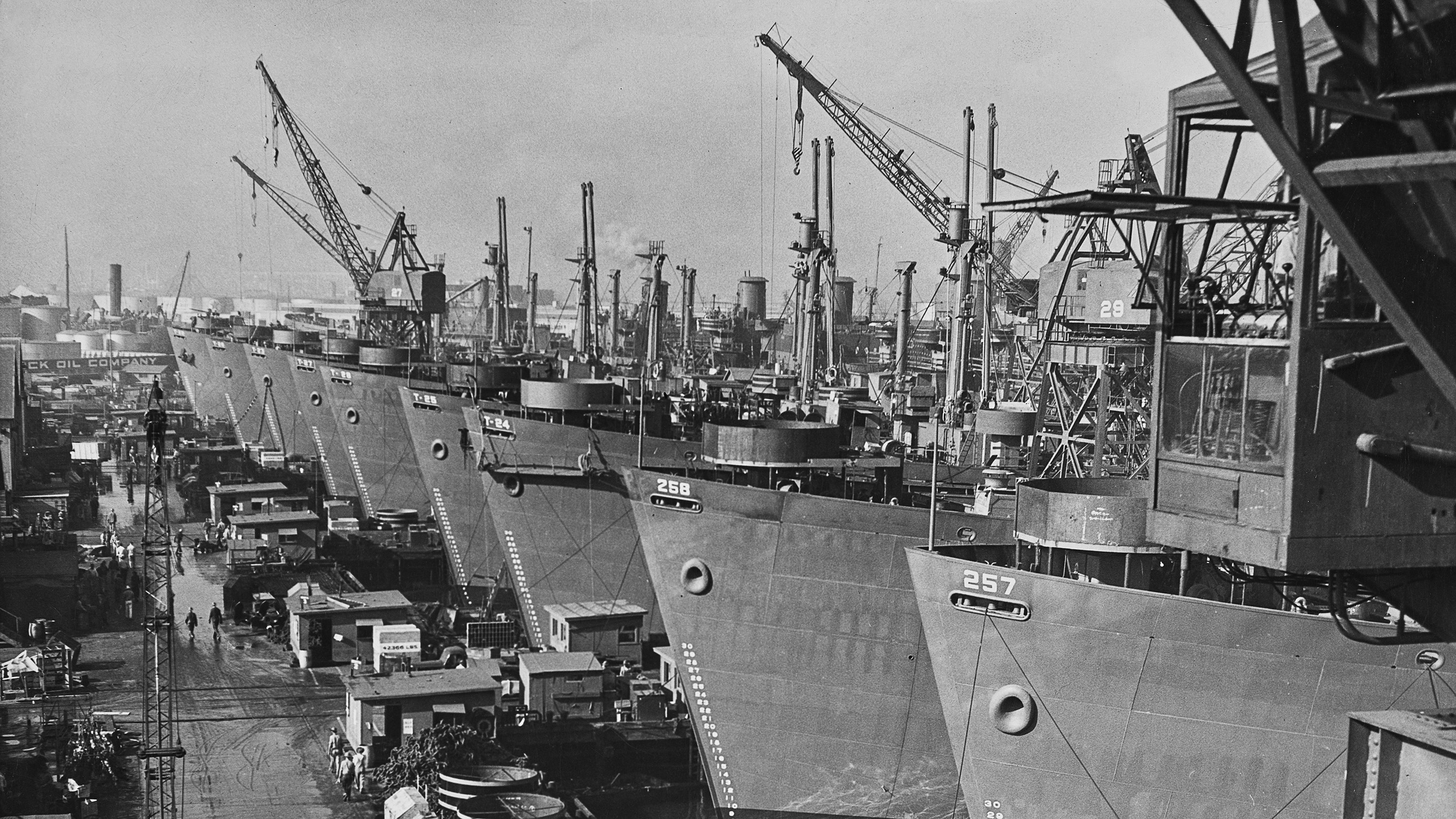 black and white picture of large cargo ships lined up in a shipyard.