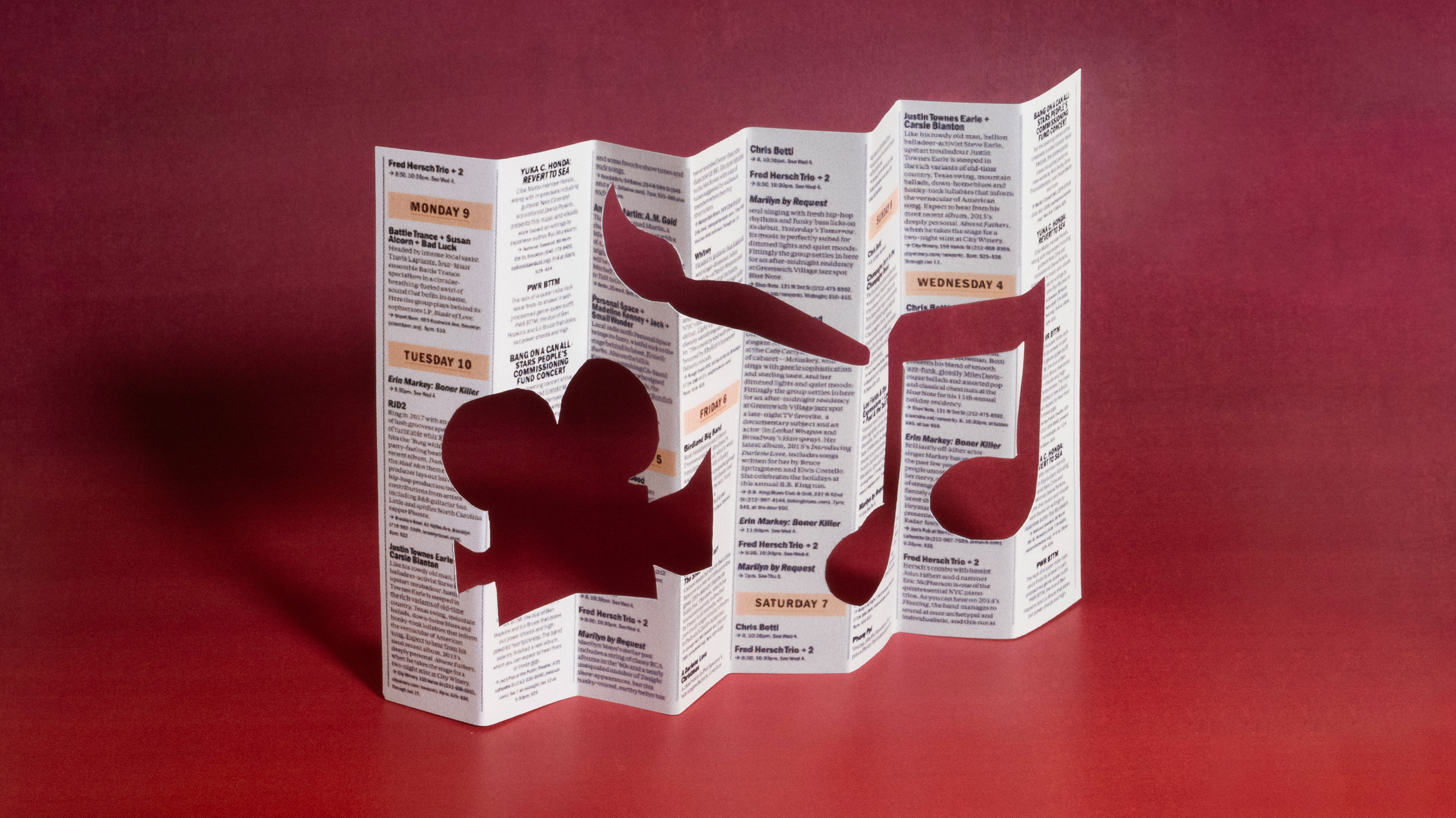 Magazine page folded like a map with a holes cut out in the shape of a movie camera, music note and paintbrush