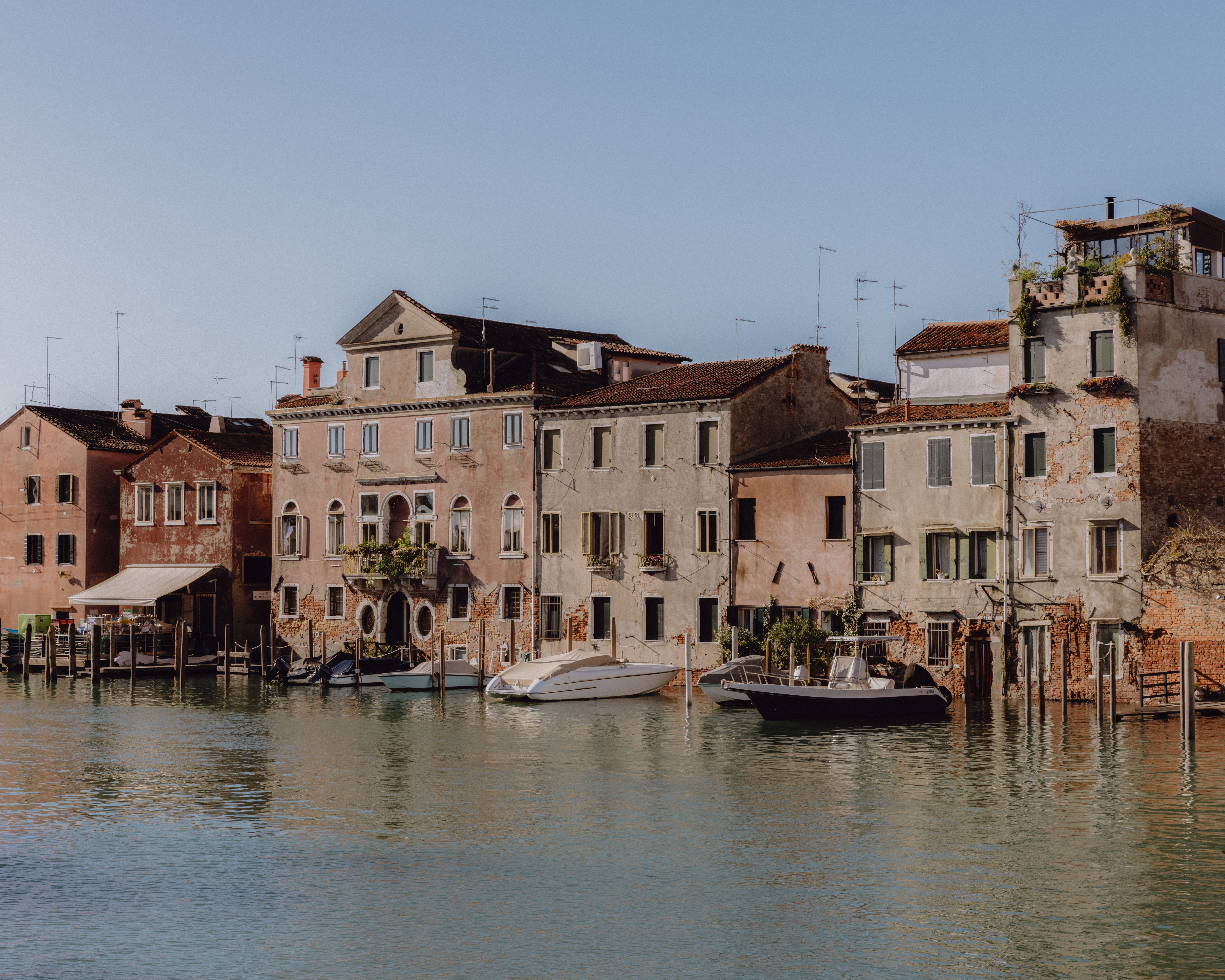 A color photograph of a Venice canal lined with stucco buildings