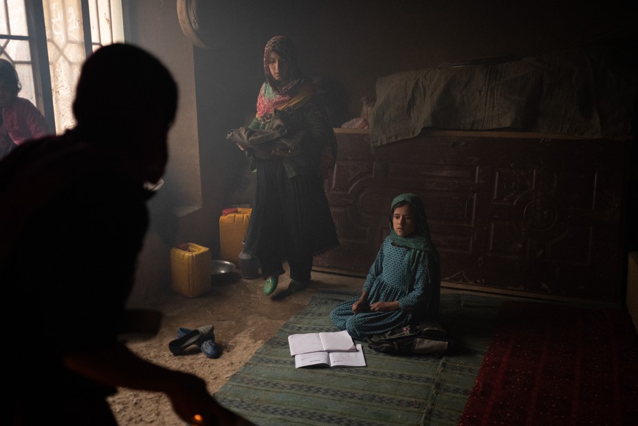 A girl sits on the floor with an open book at home