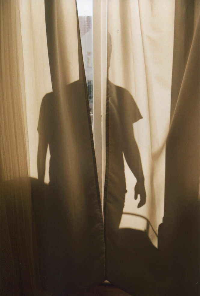 photo of the silhouette of a boy's shadow on sunlit window curtains