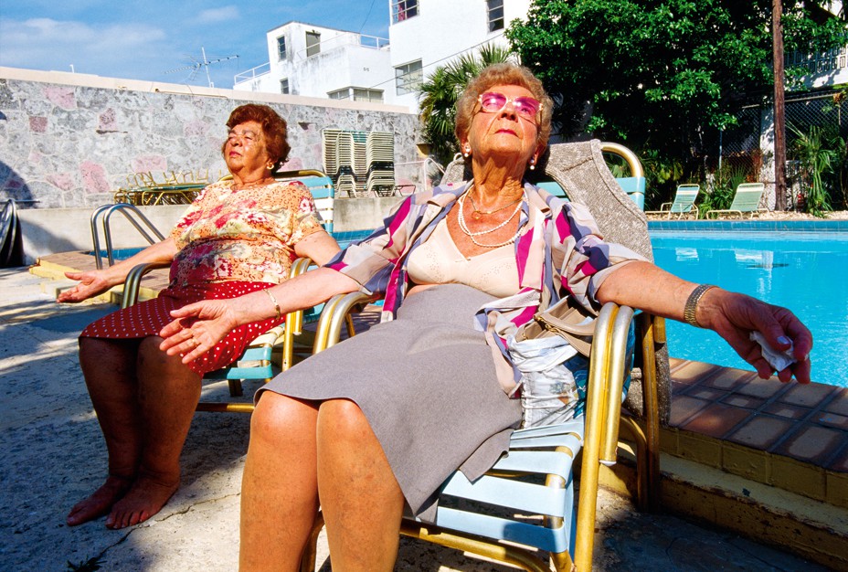 women with open blouses and skirts sunbathing by the pool
