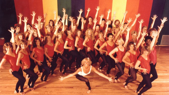 Women in red leotards pose for a group photo.
