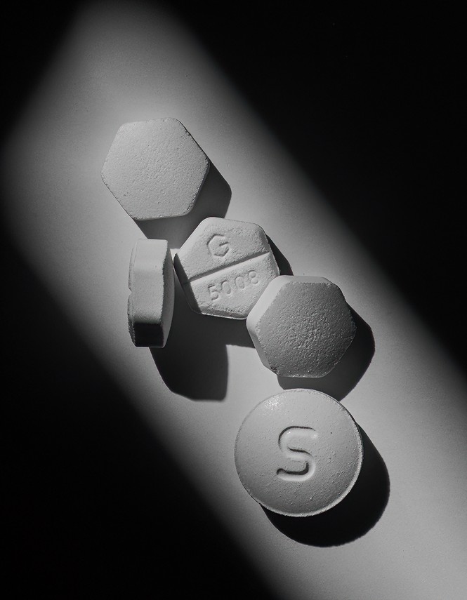 black and white photo of four hexagonal pills and one round pill