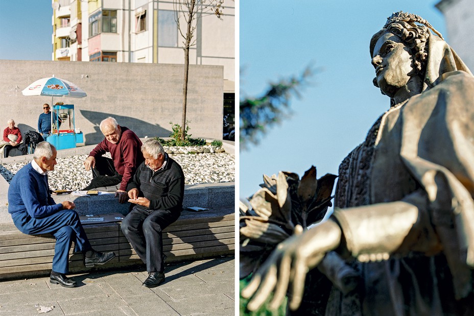2 photos: men play dominoes on a sunlit bench with a food cart and building in background; looking up from below at statue of a woman with crown and flowers, blue sky in background