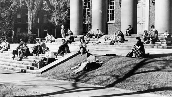 CAMBRIDGE, MA - MARCH 26: Students sit on the steps of Memorial Chapel at Harvard University on a sunny Mar. 26, 1963 in Cambridge, MA.