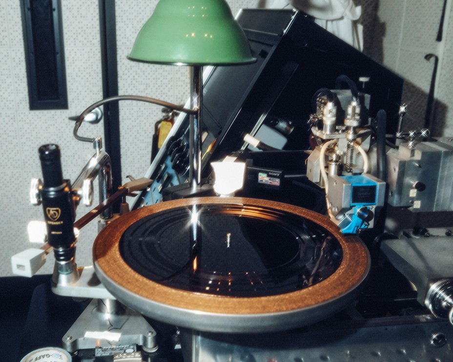 photo of a record lathe with a half-recorded vinyl disc on the turntable