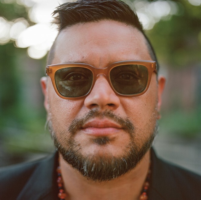 photo of man with dark hair and beard wearing sunglasses