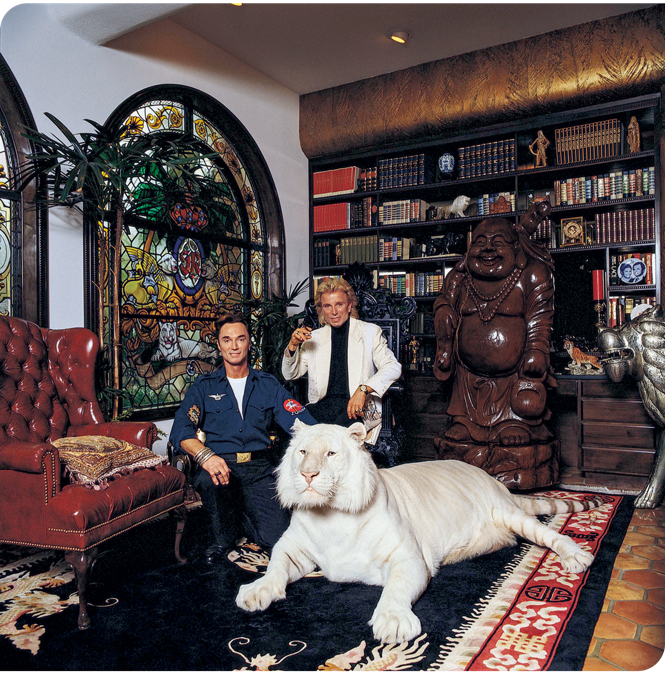 A photograph of Sigfried and Roy in their home with a white tiger.