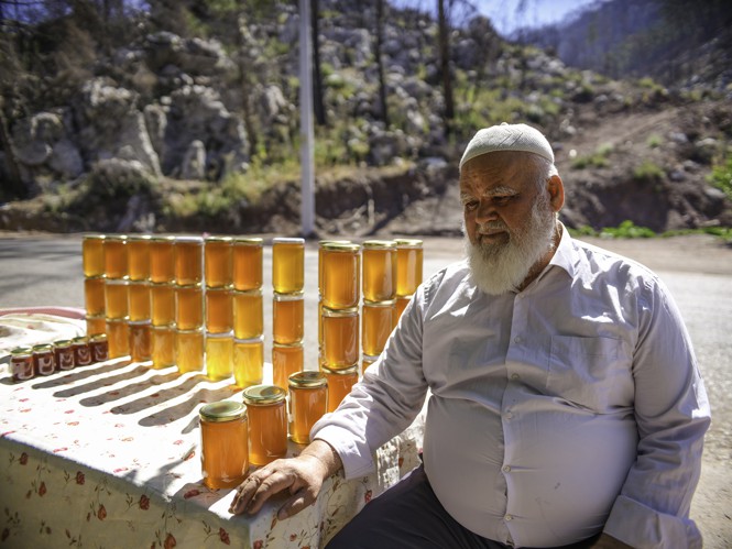 Man with honey jars on side of road