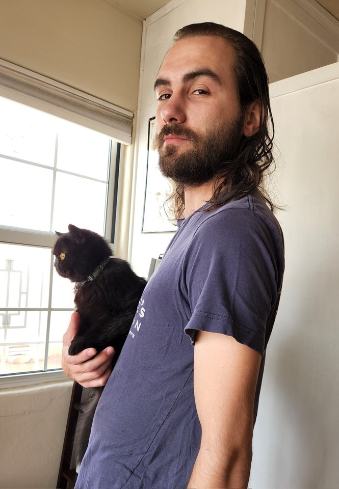 a man holding a black cat in his right arm