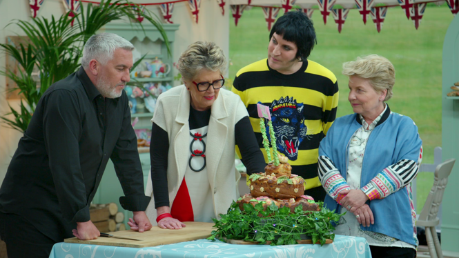 still from "The Great British Baking Show" depicting four people standing around a cake