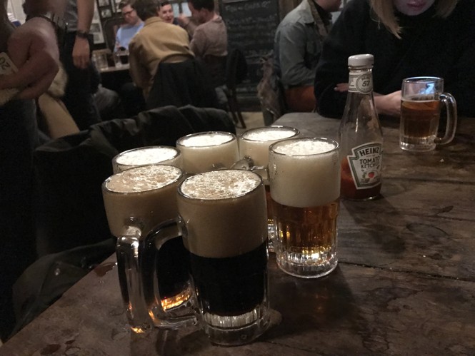 An old wooden table with glass mugs of beer on it.