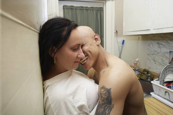 a couple smiling leaning up against kitchen wall