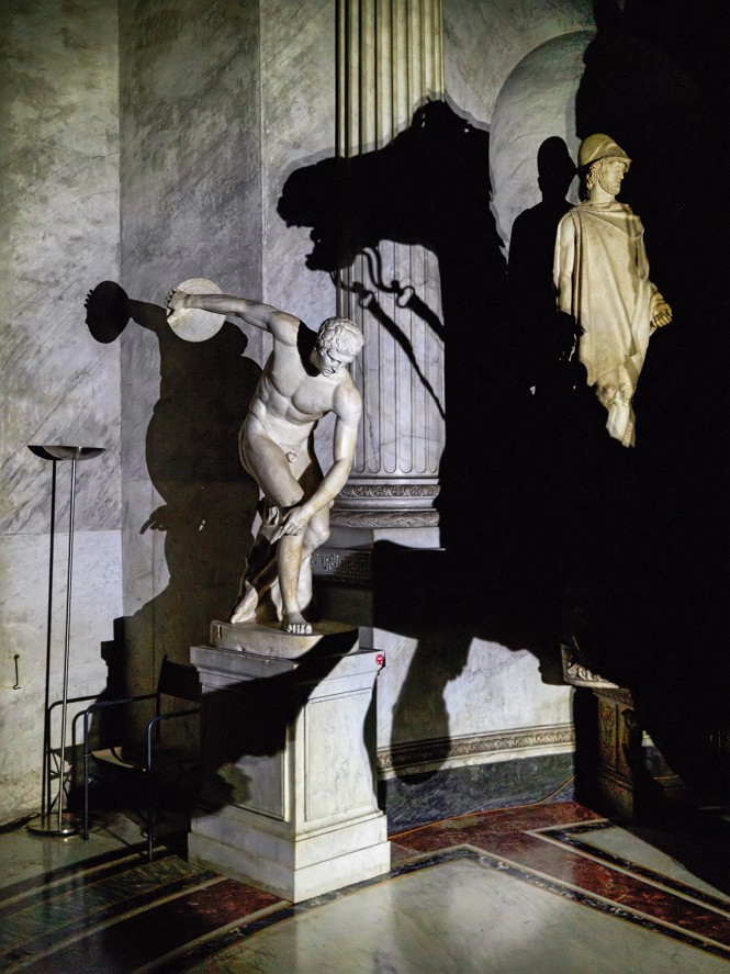 photo of statuary in hall with deep shadows: discus thrower, shadow of rearing horse, standing figure