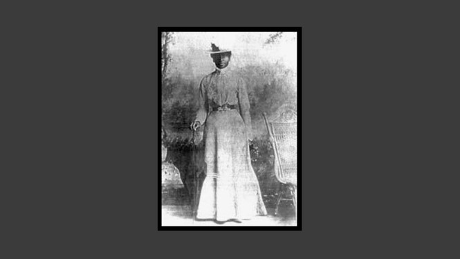A photograph from 1900 of a Black woman in a dress and hat