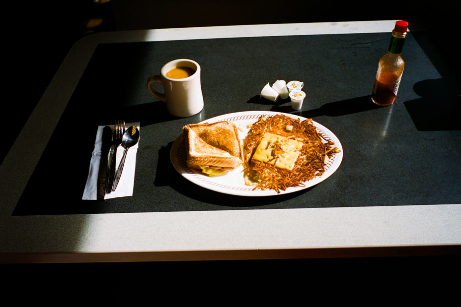 photo of diner breakfast with coffee, breakfast sandwich, hash browns, creamer packages, bottle of tabasco