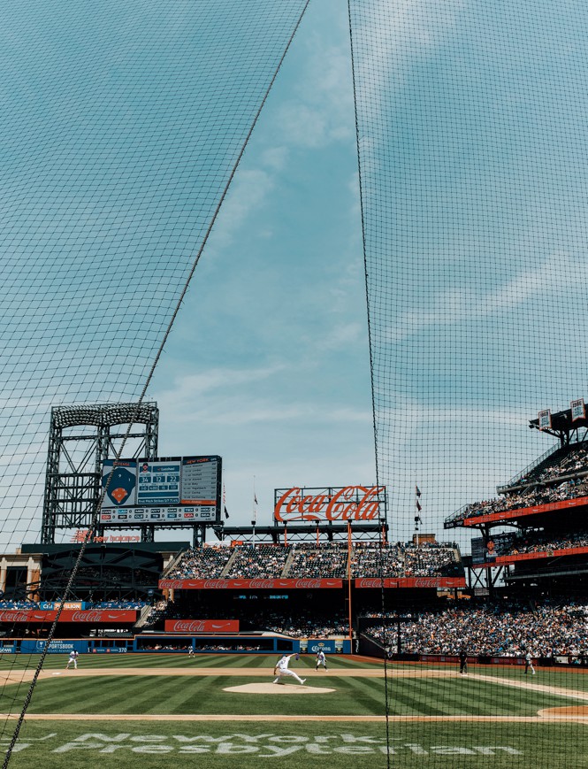 photo of baseball game with blue sky and crowded stands 