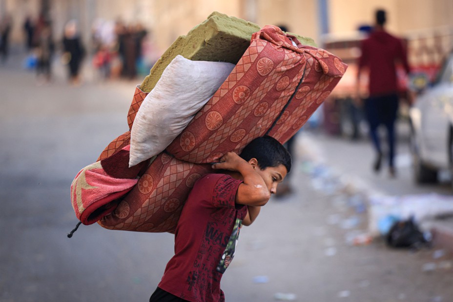 Picture of a boy carrying a mattress as Palestinians with their belongings flee to safer areas in Gaza.