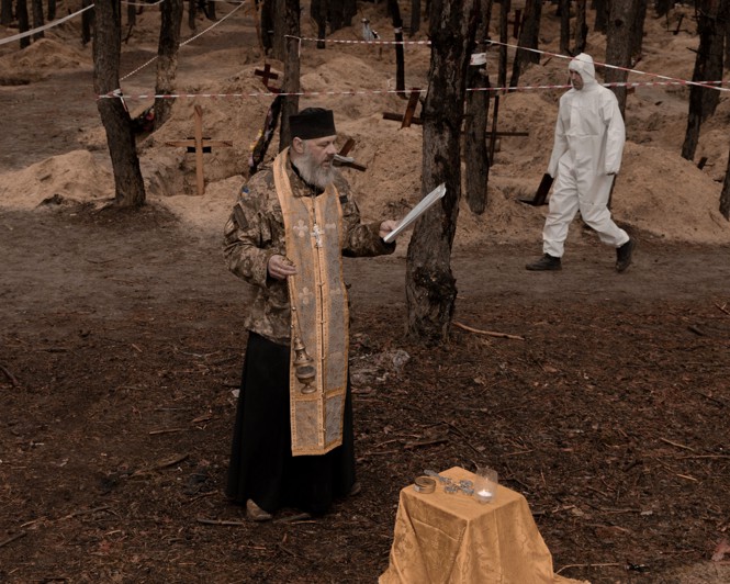 A priest performs a service near graves