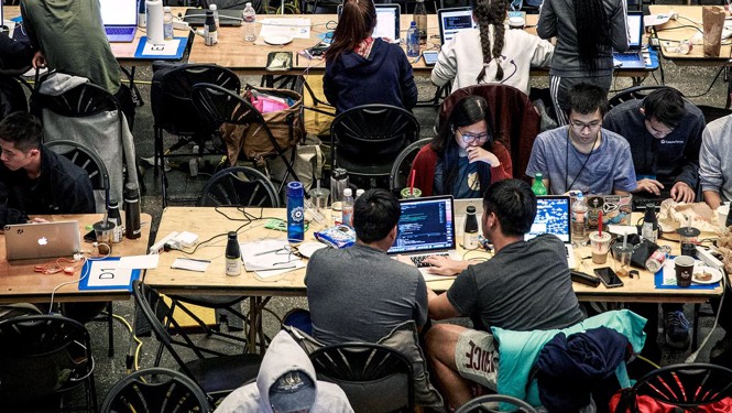 Photo of college students working at their computers as part of a hackathon at Berkeley in 2018