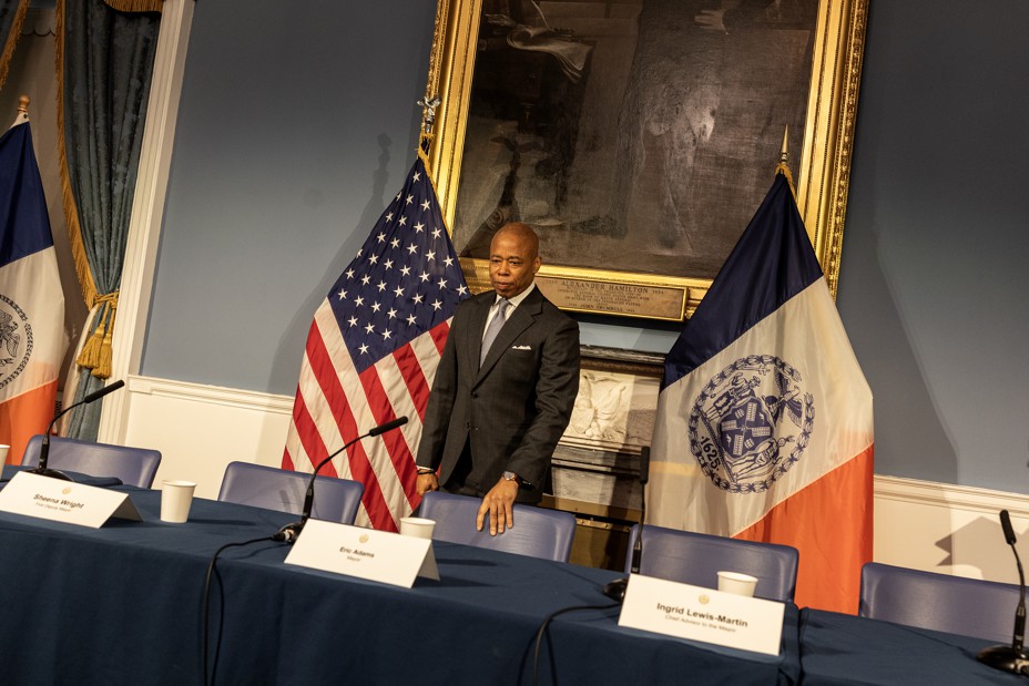 Mayor Adams stands at a table at City Hall