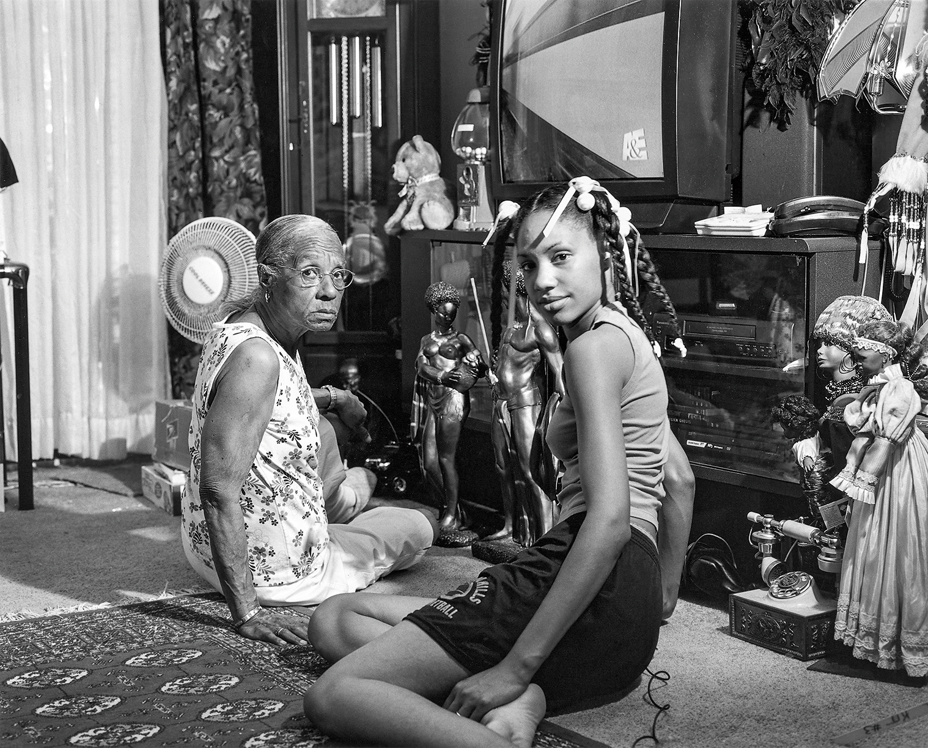 black-and-white photo of older woman and younger woman seated facing camera on living room floor