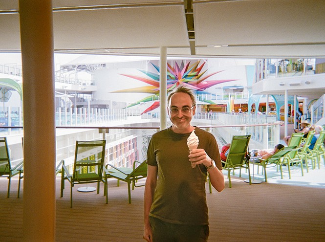 photo of author smiling and holding soft-serve ice-cream cone with outdoor seating area in background