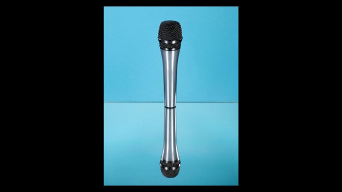 A reflective surface duplicates an image of a microphone against a blue background