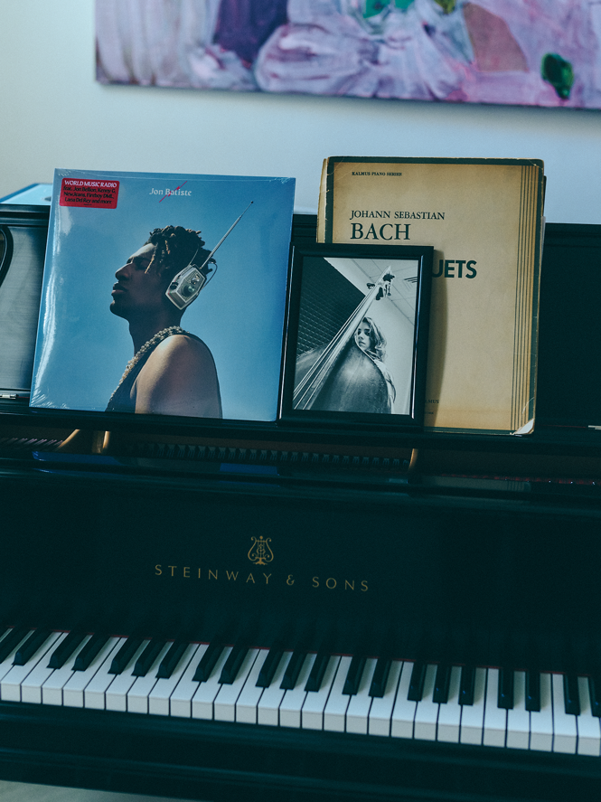 photo of piano keyboard and music rack with record album, sheet music, and framed picture of Suleika in high school holding her double bass