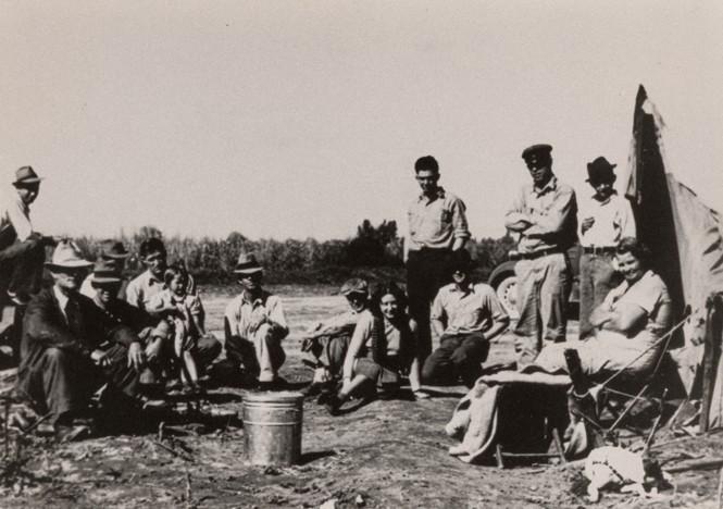 Picture of Babb (seated in center) at an FSA migrant camp, 1938.