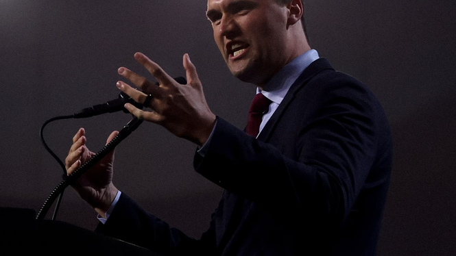 A photo of Charlie Kirk speaking at a mic with a bright orb of light above his head