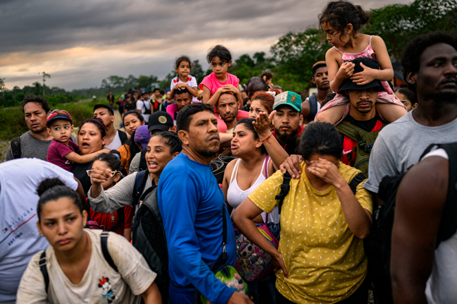 A photograph at dawn in the village of Bajo Chiquito, of a group of migrants waits to board motorized canoes, the next step in their journey north