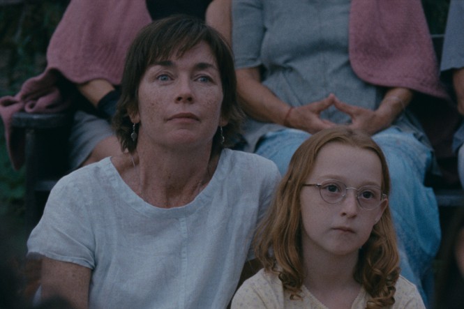 A mother and a daughter sit in front of other people