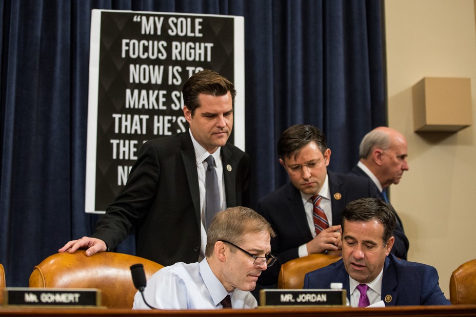 Four politicians look down at something on a table 