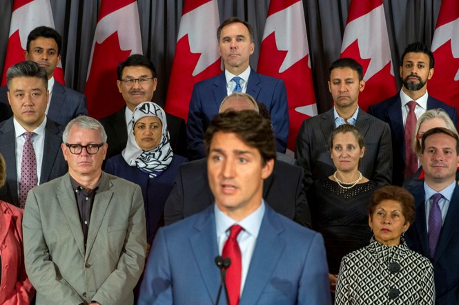 People look out on stands at Justin Trudeau who stands in front of them