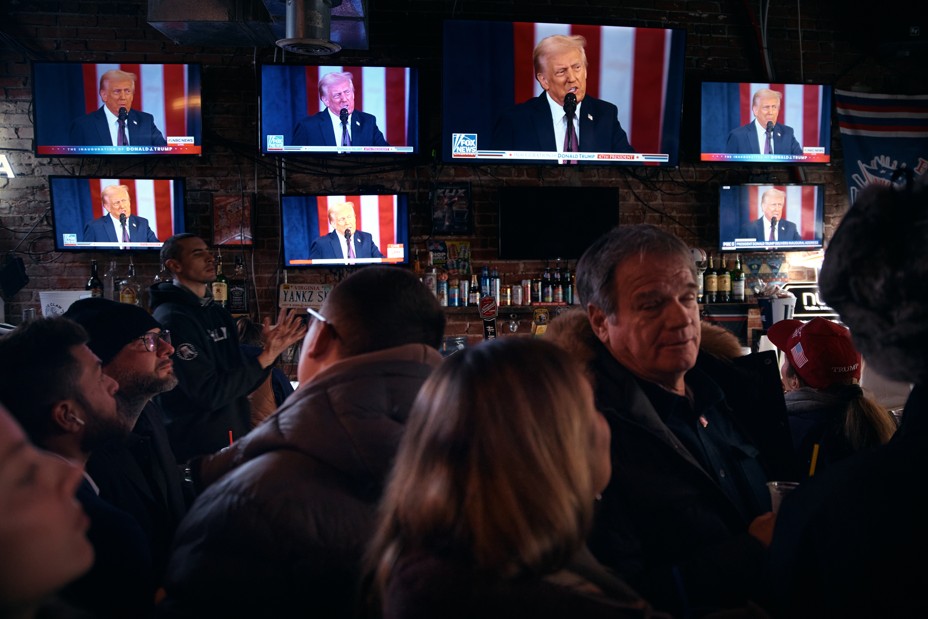 A bunch of televisions show Donald Trump at a crowded bar