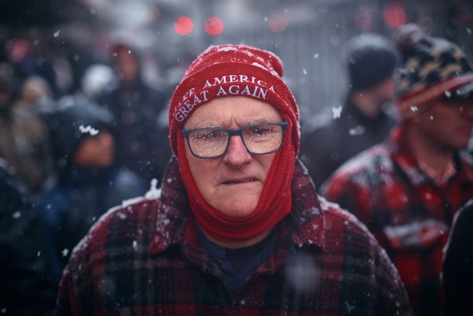 A man with a red hat stands in the snow with a group of people