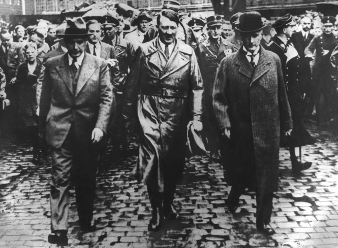 In a black and white photo Hitler walks with men outside 