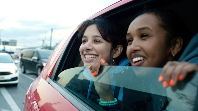 Young girls laugh looking out of a car window