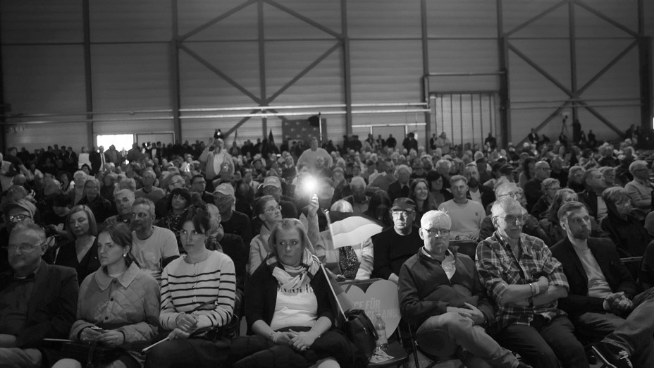 large group of people seated inside an indoor amphitheater 